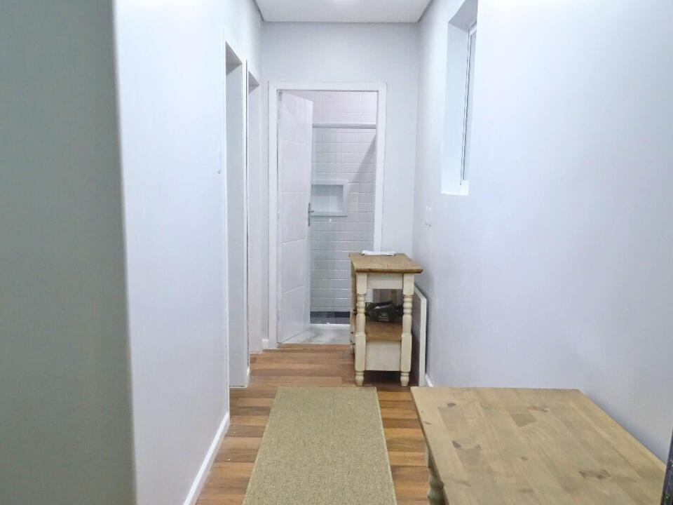 Foto do corredor do apartamento, com uma mesa para estudos e/ou trabalho e o roteador, e um aparador.